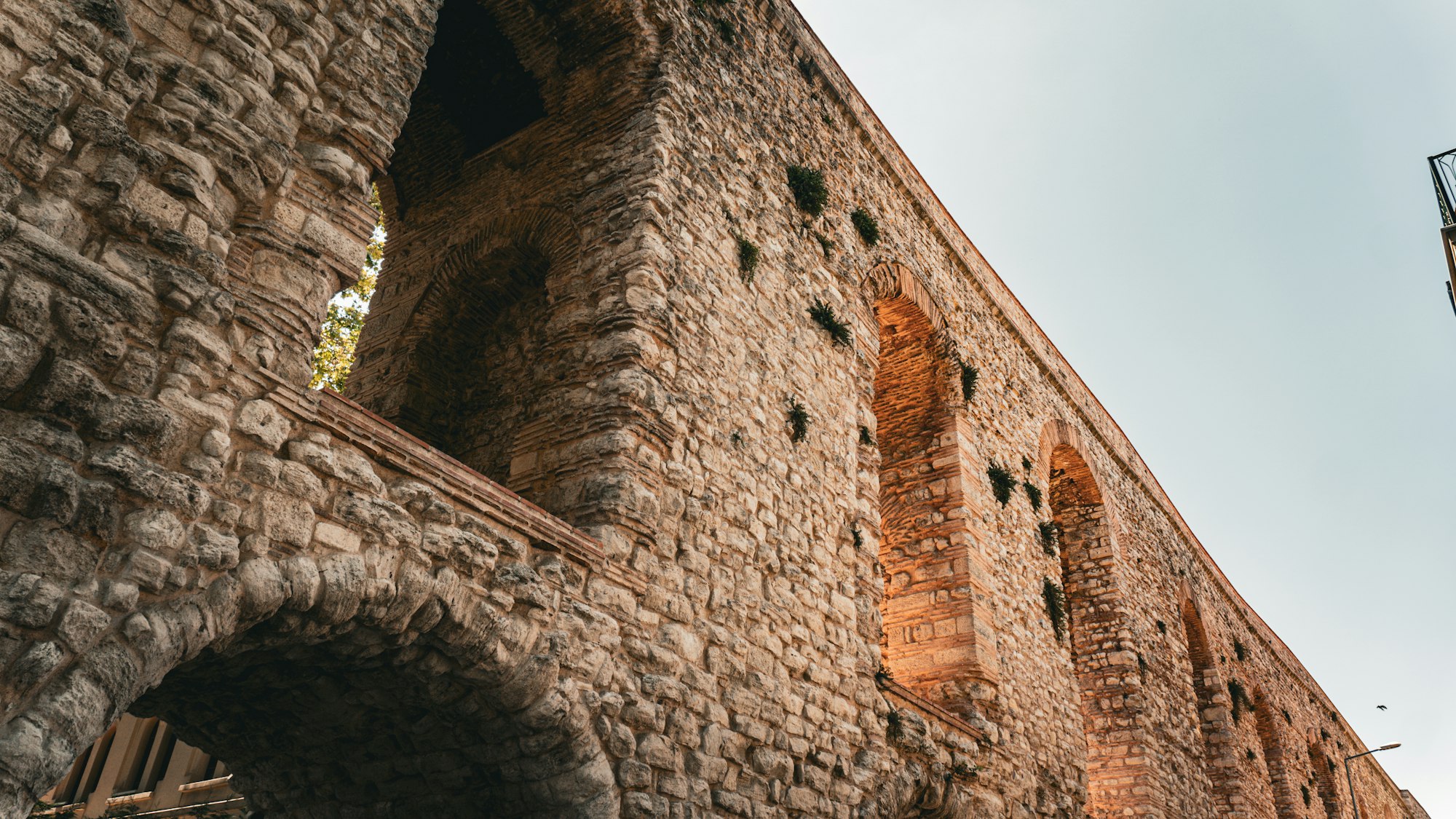 Ancient stone aqueduct with arched openings, infrastructure carrying liquidity across time